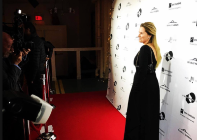 Woman standing on red carpet in front of a step and repeat backdrop