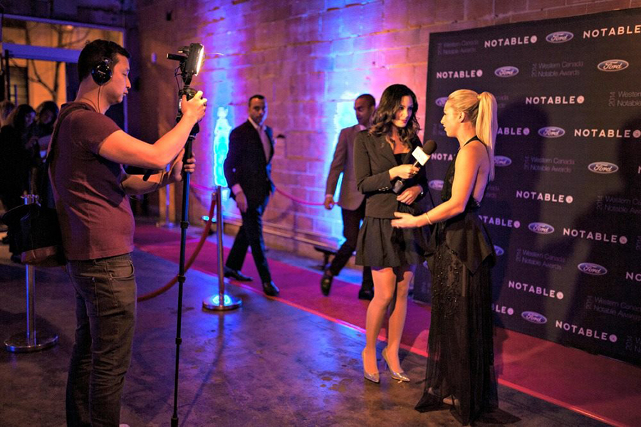 A conversation at a business marketing activation in front of a step and repeat backdrop for the brand