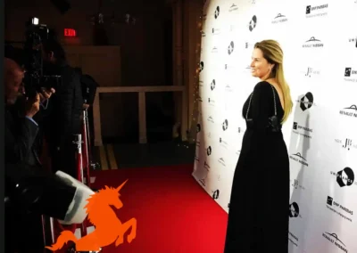 Woman standing on red carpet in front of a step and repeat backdrop